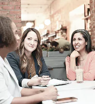 Three people seated at a restaurant table, engaged in conversation