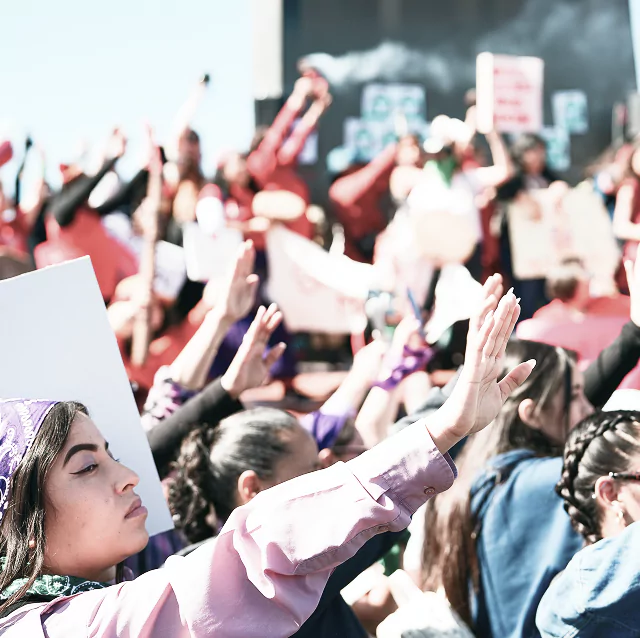 A diverse group of people standing together, holding various signs with messages
