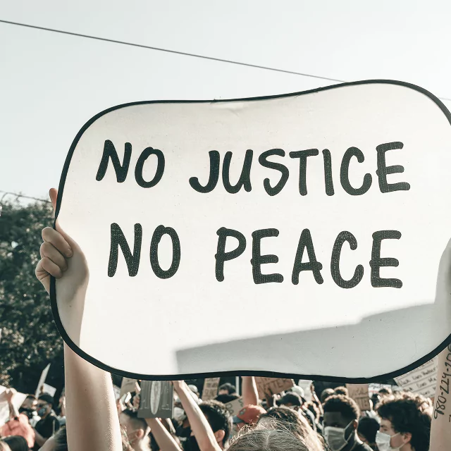 Protest sign reading "No Justice, No Peace" in bold letters