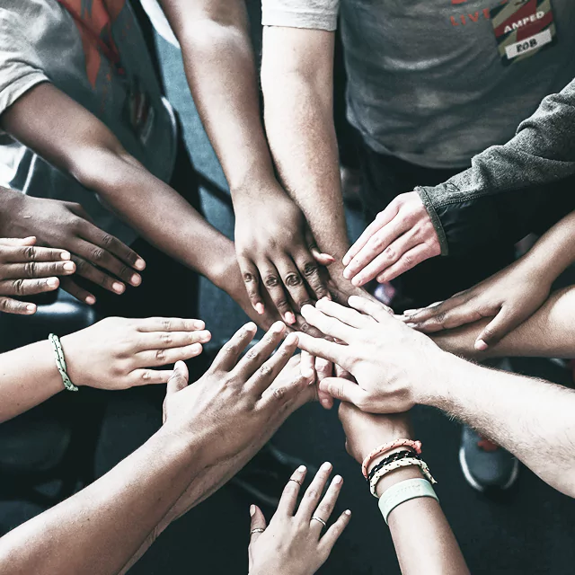 A diverse group of people standing together with their hands joined in a gesture of unity