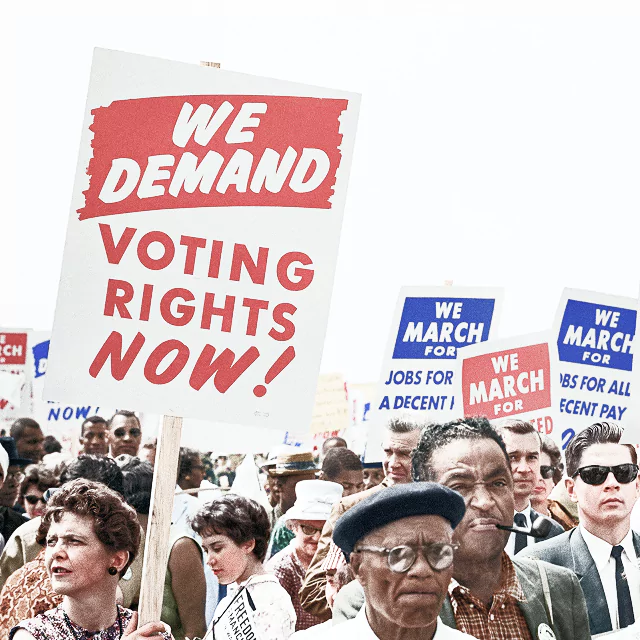 A diverse group of people standing together, holding colorful signs with various messages of support and activism.