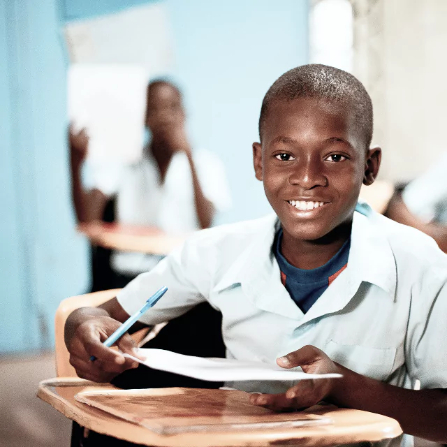 A boy seated at a desk, engaged in writing or studying