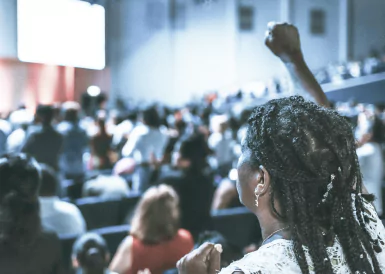 A woman raise her fist in front of a big crowd