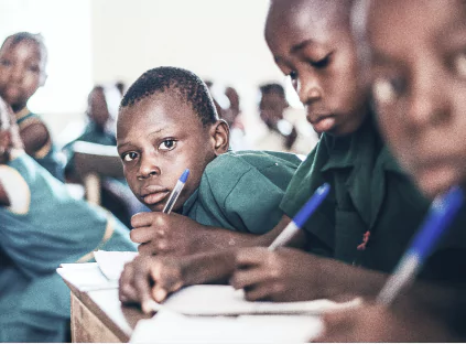A group of children attentively sitting at desks in a bright classroom