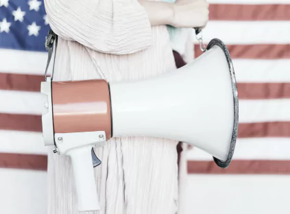 Woman holding a megaphone in front of an American flag